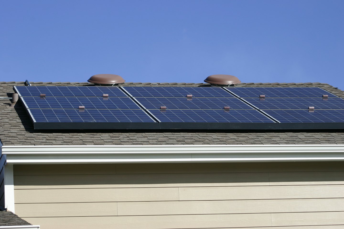 Dunkelblaue Solarmodule auf einem beigefarbenen Wohndach.